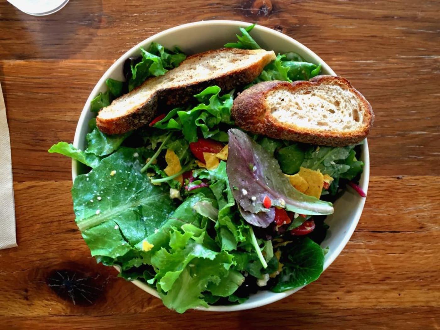Un grand bol de salade verte garni de tranches de pain grillé, vu de dessus