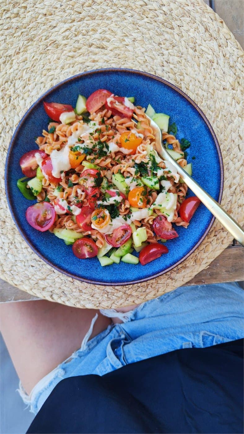 Salade colorée de pâtes de lentilles, tomates et concombre dans une assiette bleue