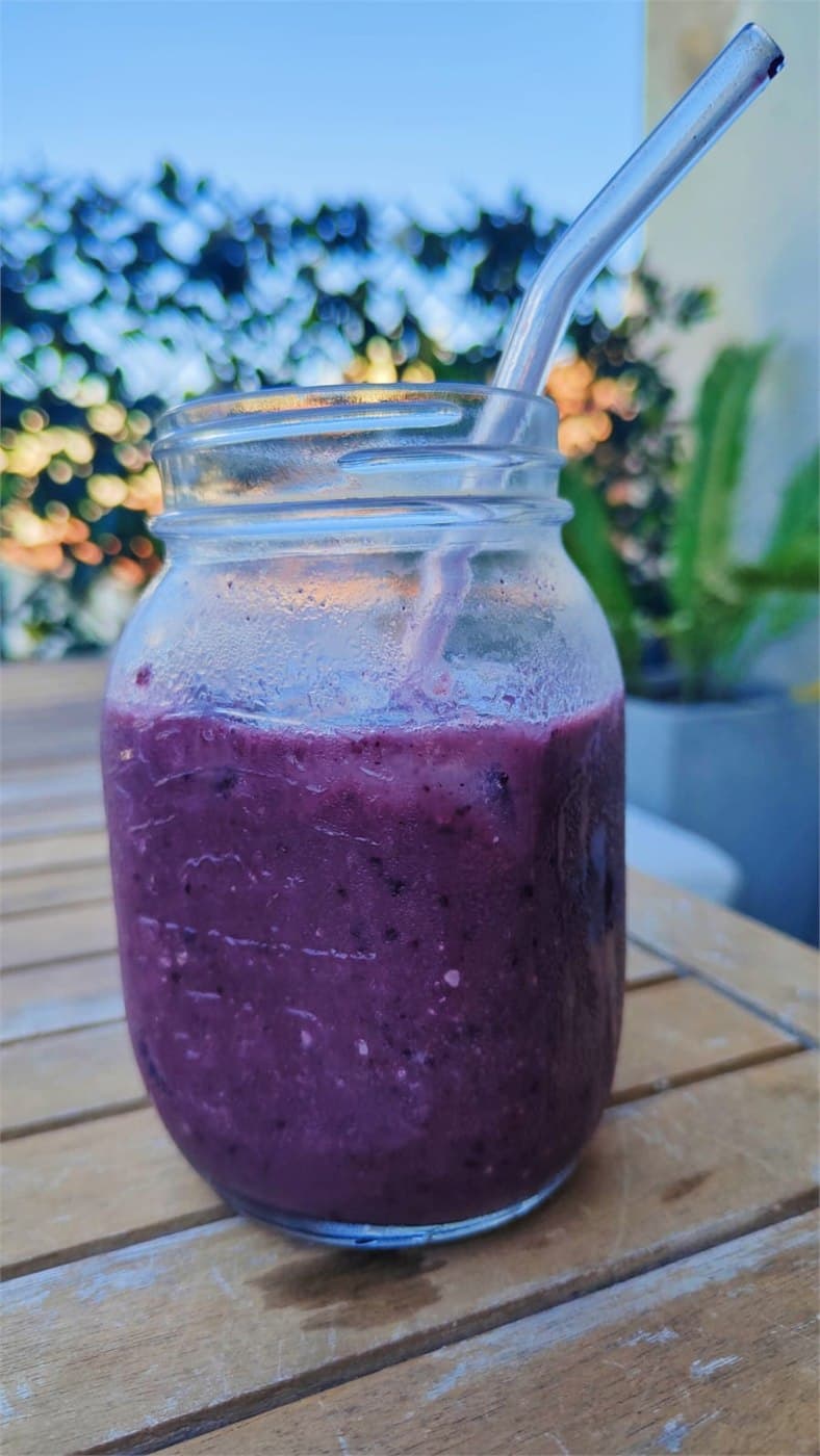 Smoothie violet aux myrtilles dans un bocal en verre avec une paille