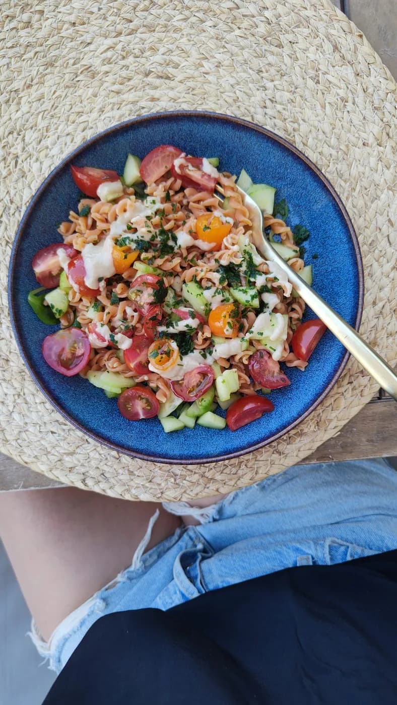 Assiette colorée de pâtes, tomates et concombre pour un déjeuner au soleil