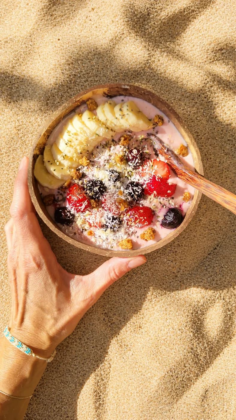 Bowl rose aux fraises, banane et fruits rouges dans la lumière du soleil