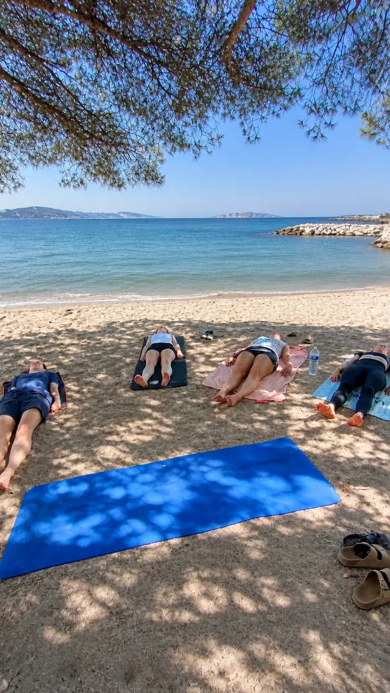 Relaxation de fin de cours de yoga sous les pins face à la mer
